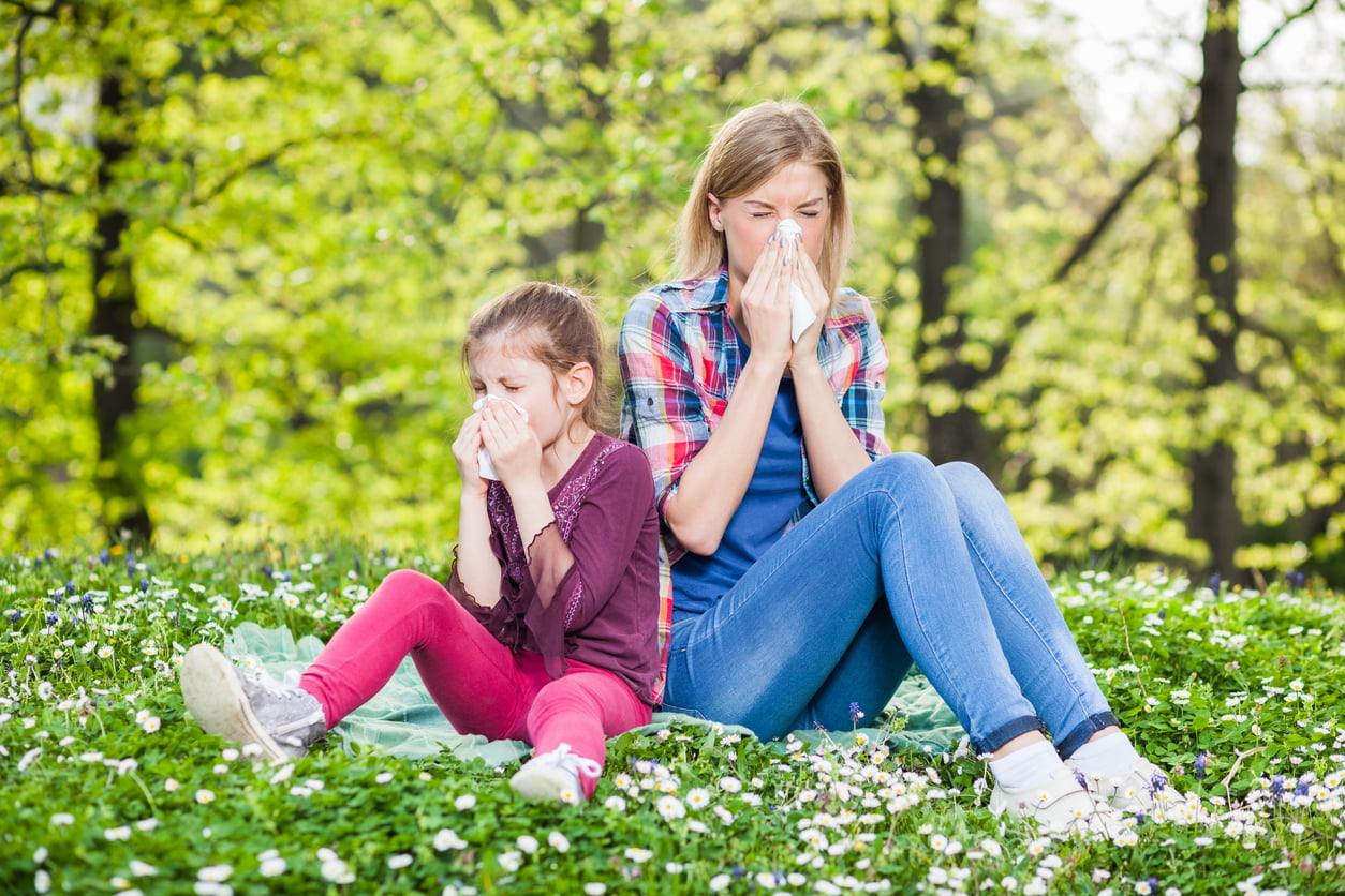 Two women with allergy symptom blowing their noses