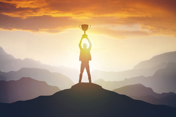 Silhouette of a man holding a trophy at sunset. Success concept